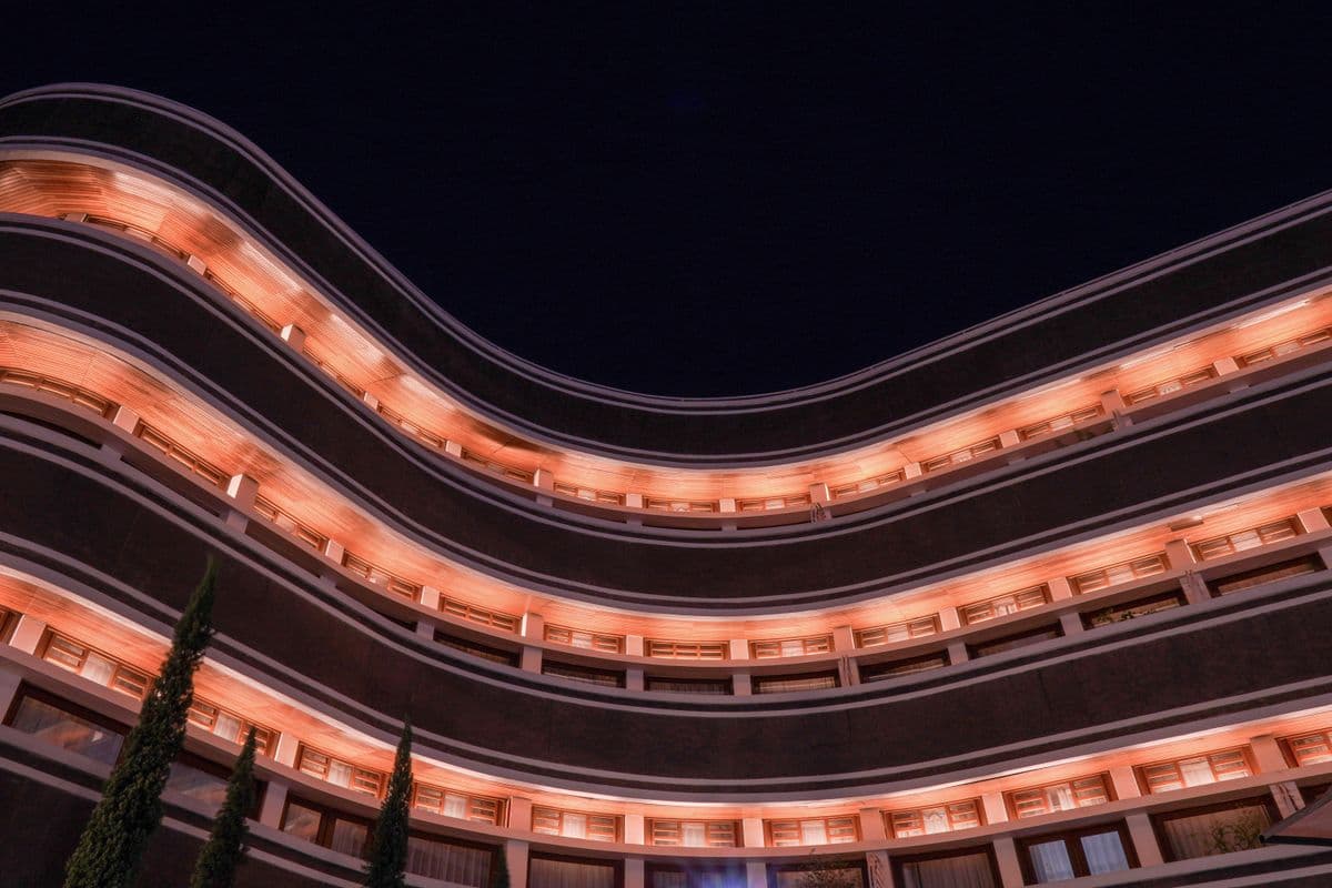 Curved hospitality building with warm balcony lighting at night