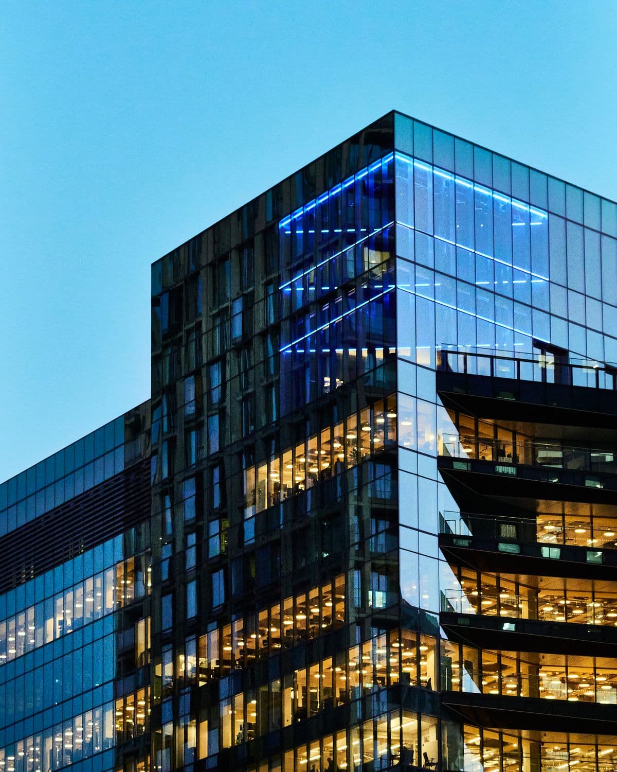 Glass commercial tower with lit office floors at dusk